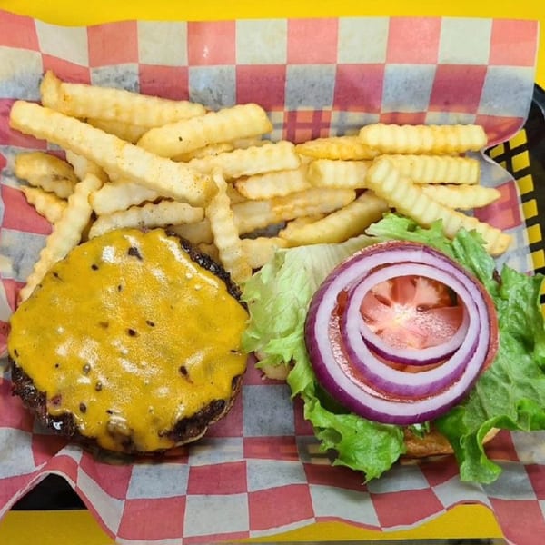 Cheeseburger with melted cheese, lettuce, tomato, and red onion, served with crinkle-cut fries.