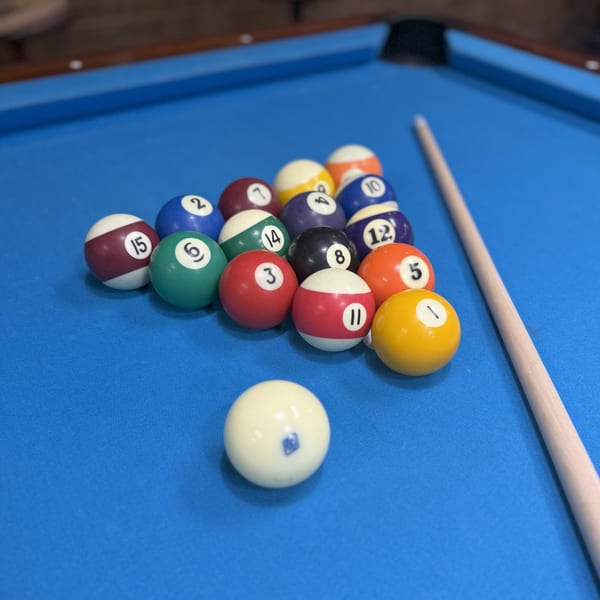 Pool table at Lucky Lou's Tavern with racked balls, cue stick, and cue ball ready for play.